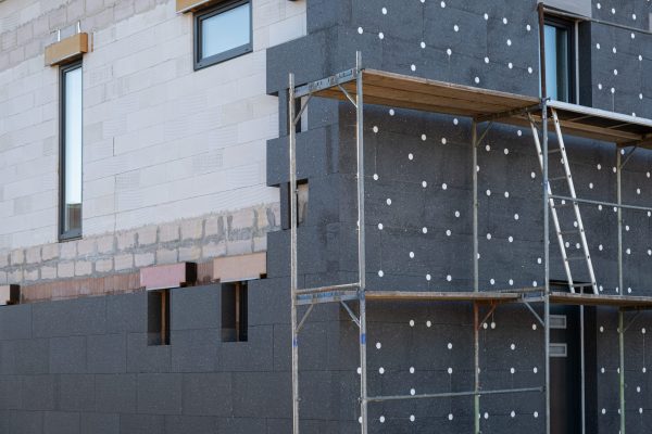 New House building in process insulation of the wall of the house with layers of modern thermal insulation materials . Exterior covering in construction site.