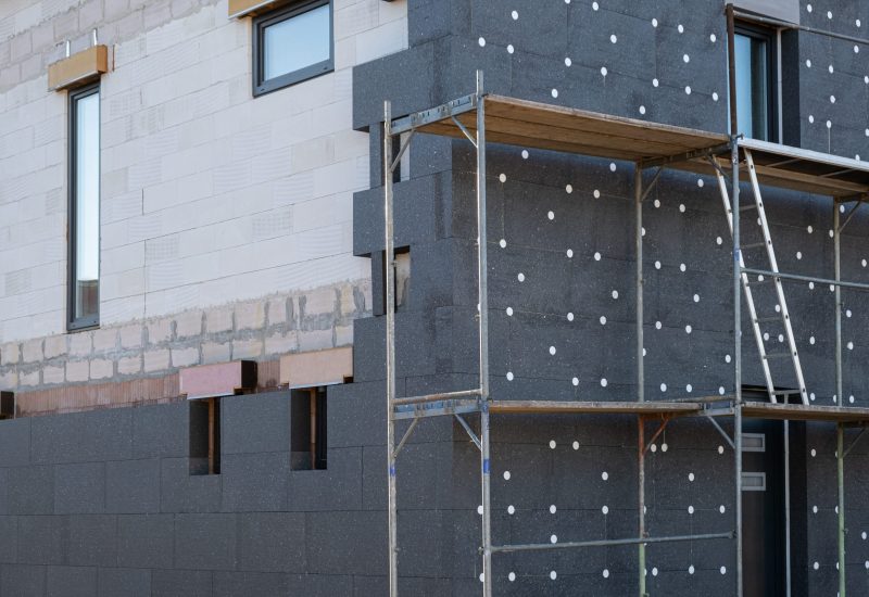 New House building in process insulation of the wall of the house with layers of modern thermal insulation materials . Exterior covering in construction site. New House building in process insulation of the wall of the house with layers of modern thermal insulation materials . Exterior covering in construction site.