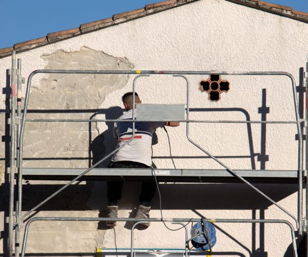 travailleurs du bâtiment faisant un ravalement de la façade d'une maison